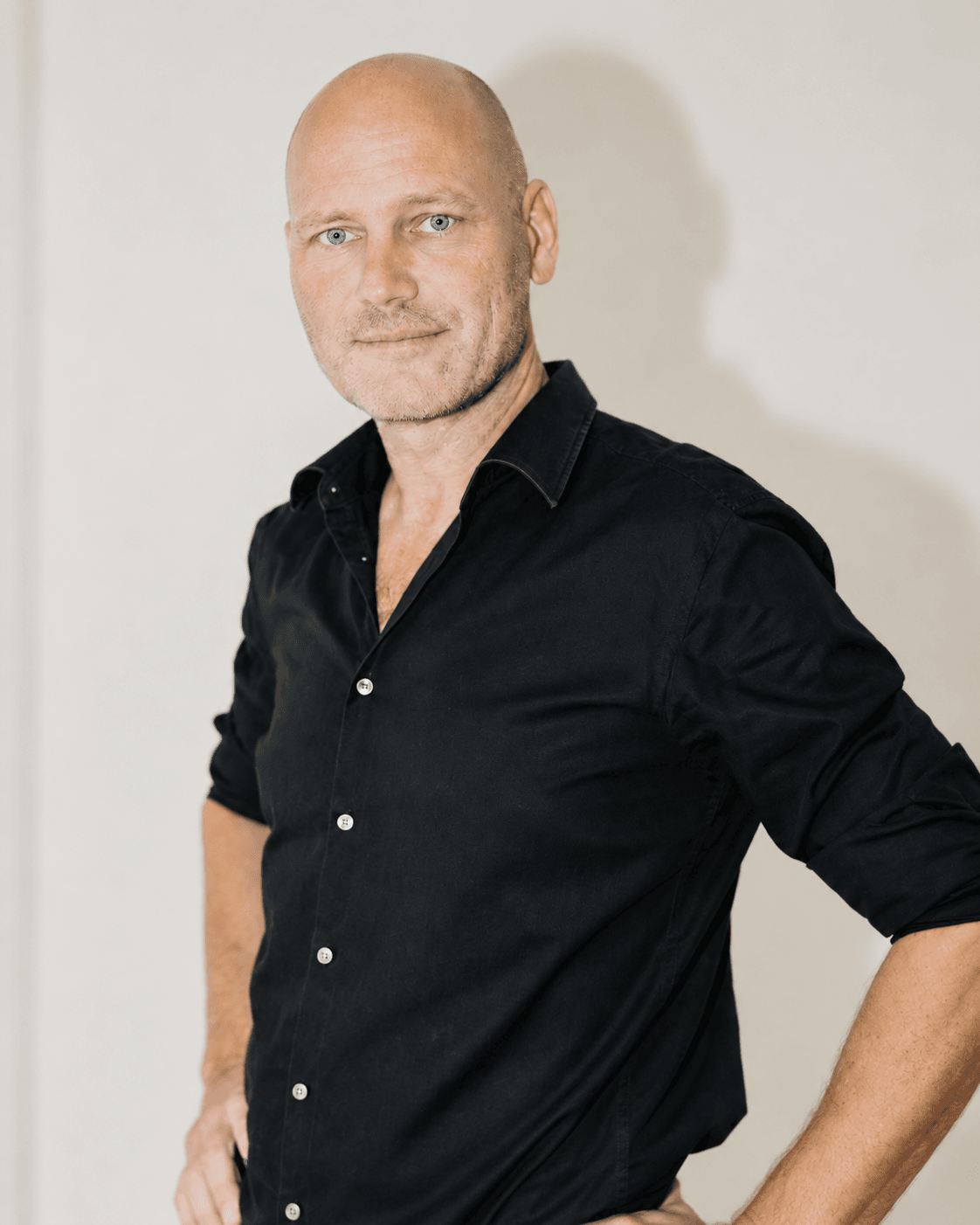 Portrait of Michael Faurholdt Friis in a black shirt against a neutral wall.