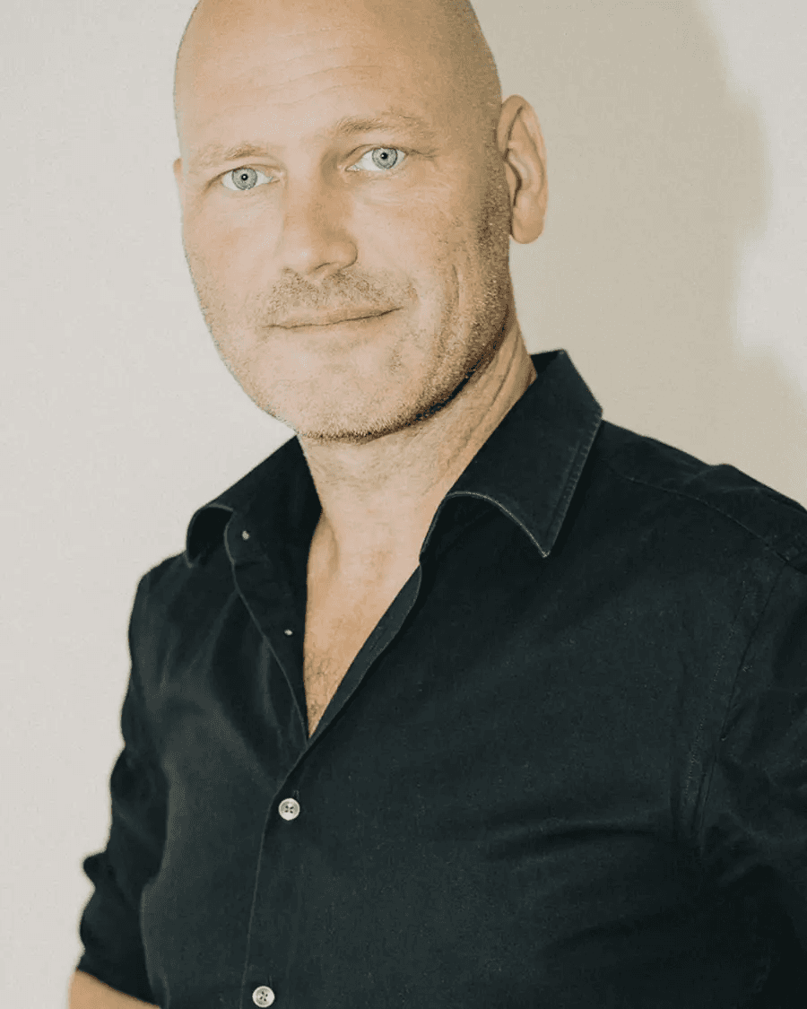 Michael Faurholdt Friis in a black shirt against a plain wall, looking towards the camera.