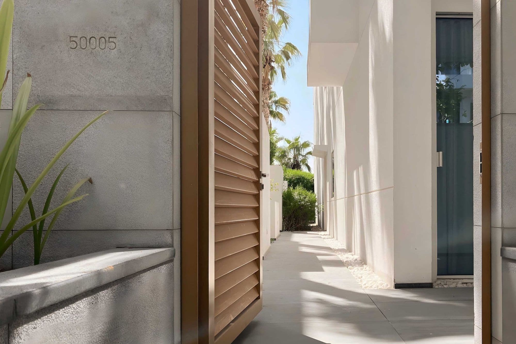 A villa entrance with timber shutters along a white-rendered passage.